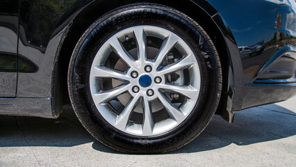 Gray car rim on the wheel of a black car	
