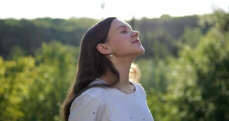 The girl breathes fresh air in nature. Positive mood from good weather and clean environment.