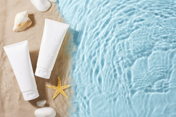 Sunscreen tubes on a sandy beach by the water, perfect for skincare product advertisements and summer travel promotions