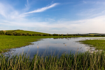 A view over a flooded field in the South Downs, with a blue sky overhead