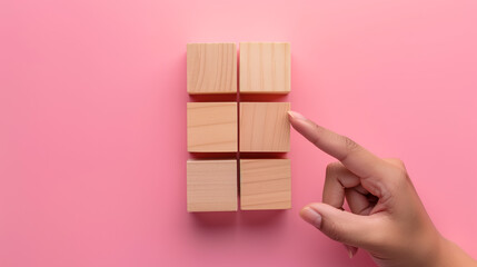 Wooden identical cubes on a pink background, and a human hand interacting with the cubes. Icons can be placed on the free faces of the cubes to emphasize the concept of this illustration.