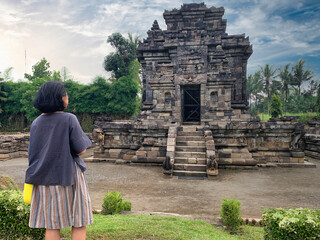 Female tourist sitting and admiring the ancient heritage of Ngawen temple in Muntilan, Central...