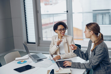 Fototapeta premium Coworkers discussing biz related problem in the office and using laptop. Conception of business team