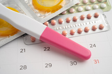 Pregnancy test and birth control pills on calendar, contraception health and medicine.