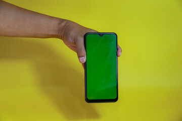 hand hold a smartphone green screen isolated on yellow background
