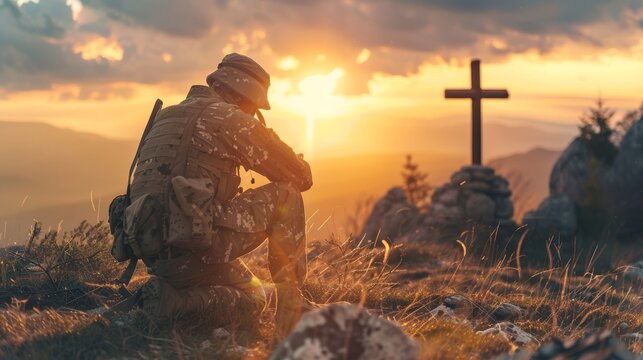 A soldier kneeling before a cross at sunset, reflecting or praying in a tranquil natural setting.