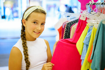 Lovely little girl happily choosing clothes in a shopping mall