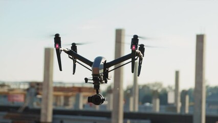 Close up footage of drone flying over construction site, observing area, machines and workers busy with tasks. Using drones in pre-construction. Outdoors