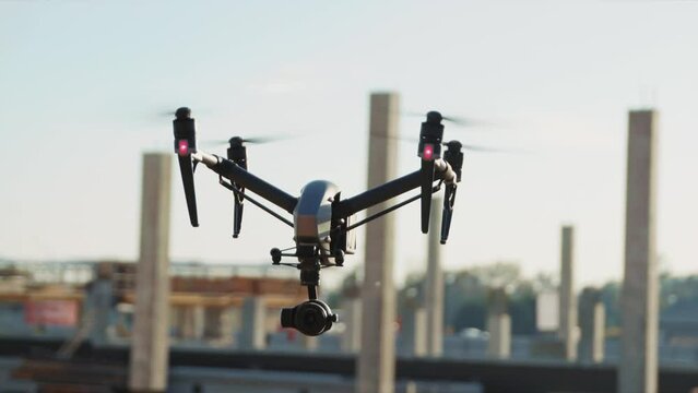 Close up footage of drone flying over construction site, observing area, machines and workers busy with tasks. Using drones in pre-construction. Outdoors