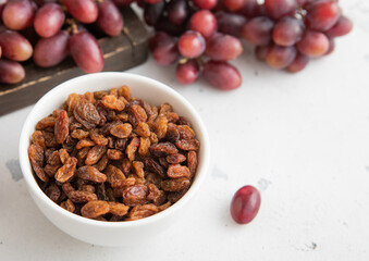 Brown dried sweet raisins on light background with red grapes.Macro