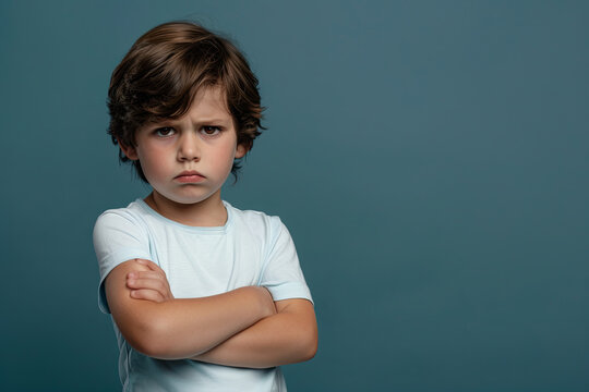 Offended young boy with arms crossed, upset expression towards camera