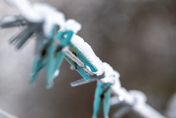 Frozen blue clothes pins on a rope under the snow on winter morning, close up. Concept of drying...