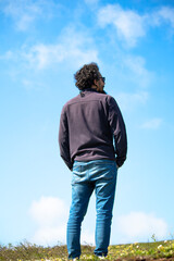 Turkish man with his back turned on blue cloudy sky background. Man looking towards