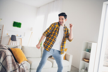 Photo of cheerful positive guy dressed plaid shirt enjoying weekend having fun indoors room home...