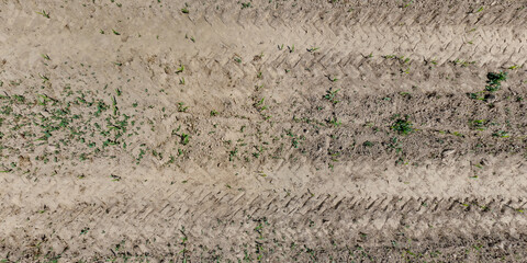 view from above on texture of dry muddy road with tractor tire tracks in countryside