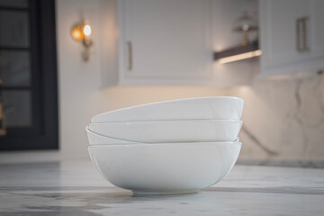 Stack of white bowls sits on a granite counter of a high end kitchen