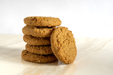 A stack of six ginger biscuits of cookies placed on a marble worktop and white background. Selective focus.  Copy space.