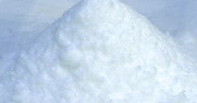 Pile of snow, white snowdrift. Snow falls from snowmaking apparatus. Ice flake making machine. Snow making machine produce artificial snow. Snow production technology