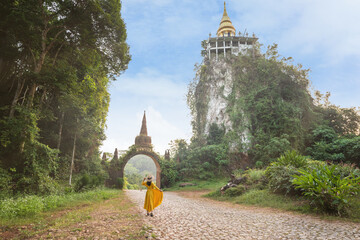 Asian female tourist in yellow dress and hat at The large ancient pagoda arch is beautiful, Khao Na...