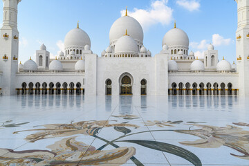 The majestic white marble domes of Abu Dhabi&rsquo;s iconic mosque against a clear blue sky.