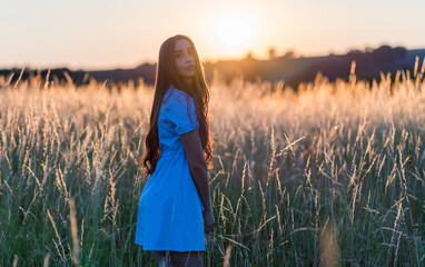 girl with long hair in a short dress in a field during sunset