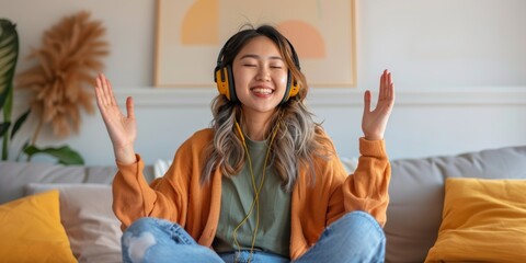 Positive woman at home listening to youth radio, mental health music, and streaming on sofa with headphones. Asian youth or Kpop fan relaxing with audio technology in living room, couch, or apartment.