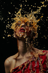 Woman in red dress covered in honey on black background.