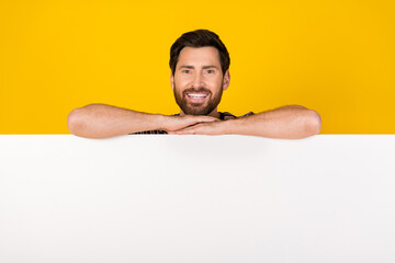 Photo of young adult bearded man folded hands billboard empty blank space information isolated on yellow color background