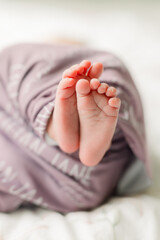A newborn baby is sleeping with her feet curled up in a blanket. 