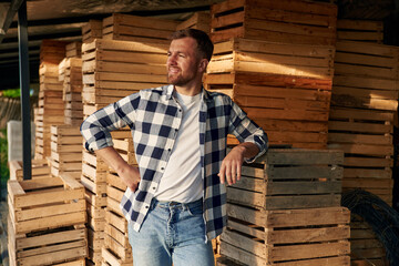 Man farmer is indoors in the storage with wooden boxes