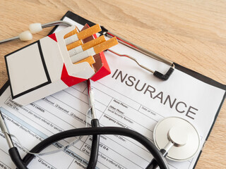 Cigarettes and stethoscope on insurance documents