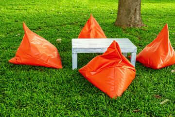 Beautiful view of orange triangle bean bags and cushions with white wooden table for customers to...