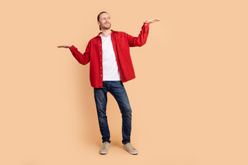 Full size photo of nice young man hands hold empty space wear red shirt isolated on beige color background