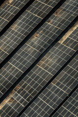 Aerial view of a solar farm with rows of solar panels arranged in a precise, repetitive pattern. Highlight the clean lines and geometric shapes, using a minimalist composition. 