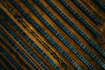 Aerial view of a solar farm with rows of solar panels arranged in a precise, repetitive pattern. Highlight the clean lines and geometric shapes, using a minimalist composition. 