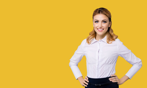Portrait image of happy smiling businesswoman, with empty area for text. Confident blond woman wear white shirt standing in hands on hips pose, isolated yellow background. Business ad concept.