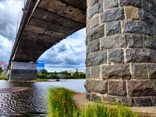 Expansive Bridge Arching Over River With Cloud-Filled Sky on a Bright Day