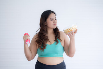 chubby Asian woman holding dumbbells in hand and popcorn