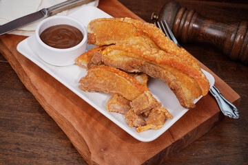Thai food. Crispy fried pork belly cut into pieces on a wooden table.