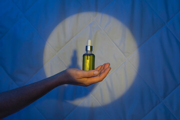 woman hand on the background of a quilt in the light of the moon with dropper with sleeping oil....