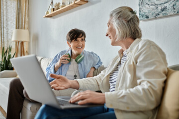 Two women engage in a deep conversation on a laptop while seated on a comfortable couch.
