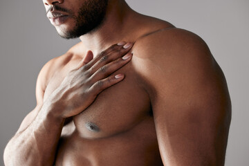Hand, chest and black man in studio with muscle, topless and healthy body on gray background. Male...