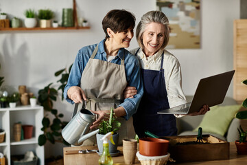 Two women in aprons engage with a laptop.