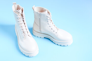 White demi-season martens boots with a bouquet of spring flowers on a light blue.