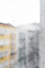 Raindrops on the window glass from the side of the apartment during the day