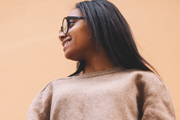 Smiling afro american young hipster girl in stylish eyeglasses in trendy sweatshirt with copy space...