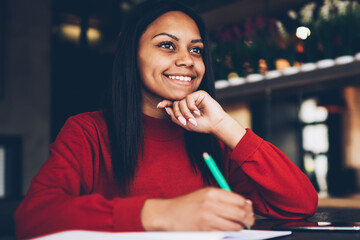 Cheerful afro american businesswoman satisfied with incomes accountings while sitting in cafe...