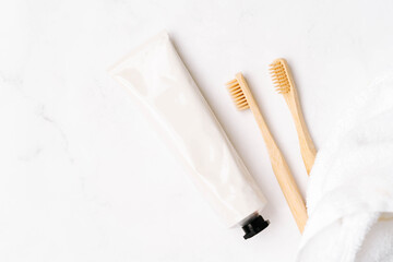 Top view of white metal tube without label and toothbrushes on white background