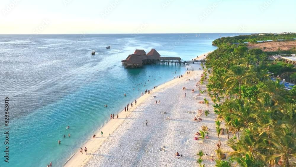 Sticker Aerial view of beautiful bungalow in Indian ocean at sunset in summer. Restaurant on the sea. Top drone view of wooden hotel, palm trees, azure water, white sandy beach. Travel in Kendwa, Zanzibar