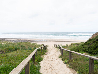 Wooden walkway over the sand of the beach dunes aimed at the empty ocean beach